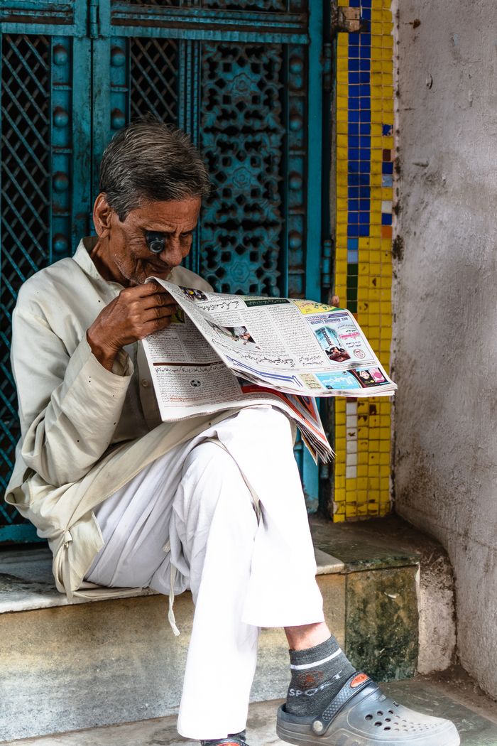 Crafting Captivating Headlines: Your awesome post title goes here A senior man enjoys reading a newspaper while sitting on an urban sidewalk.