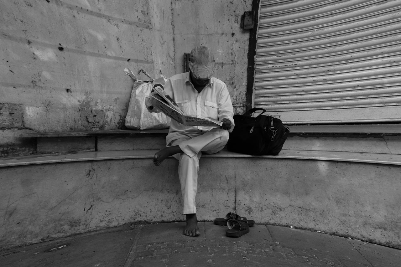 Mastering the First Impression: Your intriguing post title goes here A man sits on a bench in Mumbai, engrossed in reading a newspaper. Monochrome tone.